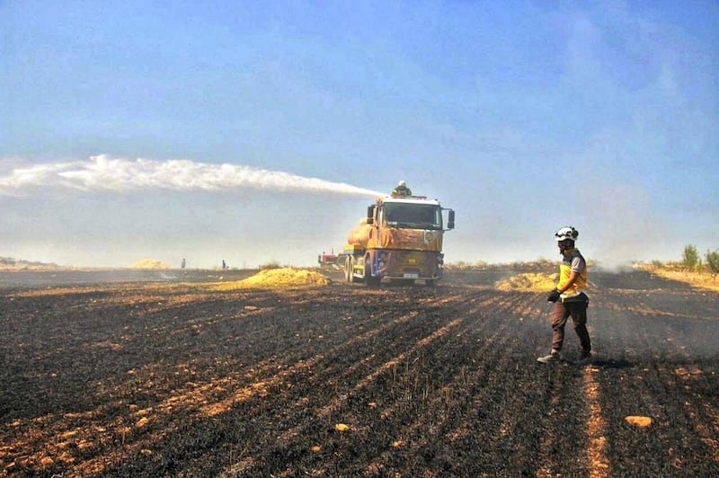 This Tuesday, May 28, 2019 photo, provided by the Syrian Civil Defense White Helmets, which has been authenticated based on its contents and other AP reporting, shows Syrian White Helmet civil defense workers trying to extinguish a fire in a field of crops, in Kfar Ain, the northwestern province of Idlib, Syria. Crop fires in parts of Syria and Iraq have been blamed on defeated Islamic State group militants in the east seeking to avenge the group‚Äôs losses, and on Syrian government forces in the west battling to rout other armed groups there. (Syrian Civil Defense White Helmets via AP)