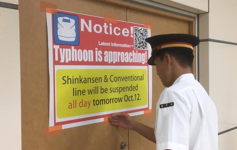 A railway staff member tapes a poster that reads "Typhoon is approaching" to a wall at a station in Kakegawa. Reuters