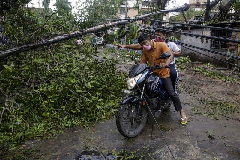 People make their way through damaged cables and a tree branch fallen in the middle of a road after Cyclone Amphan hit the region in Kolkata, India. A powerful cyclone ripped through densely populated coastal India and Bangladesh, blowing off roofs and whipping up waves that swallowed embankments and bridges and left entire villages without access to fresh water, electricity and communications. AP Photo