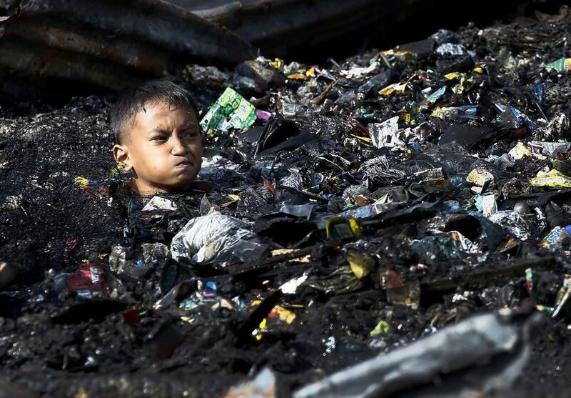 A Filipino boy collects salvageable materials among debris following a fire that razed a slum area in Malabon City, north of Manila, Philippines. Dennis Sabangan / EPA
