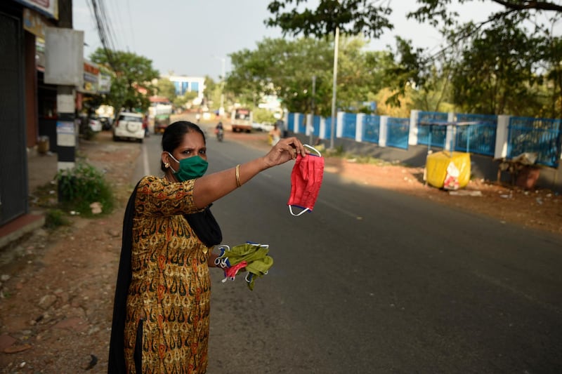 A woman waves a face mask to attract prospective buyers among commuters as she sells them outside a shop in Kochi, Kerala. AP Photo