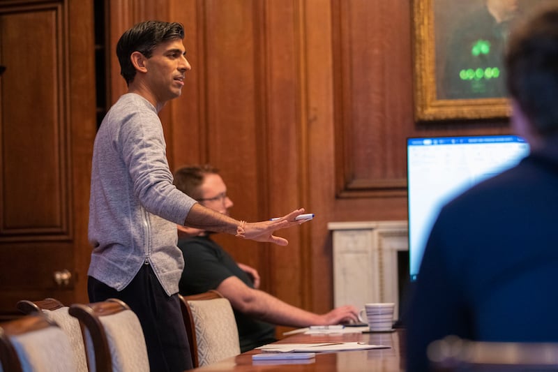 In a grey jumper, white socks and black sandals available for £95 ($131) from Palm Angels, Rishi Sunak works on his speech.