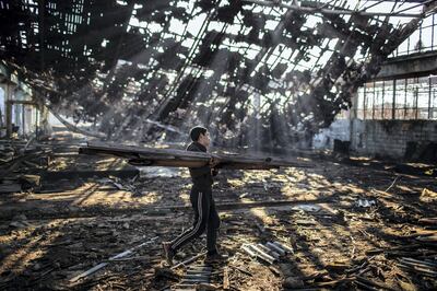 An Afghan migrant collects wood to make a bonfire in an abandoned factory in the Bihac industrial area.

