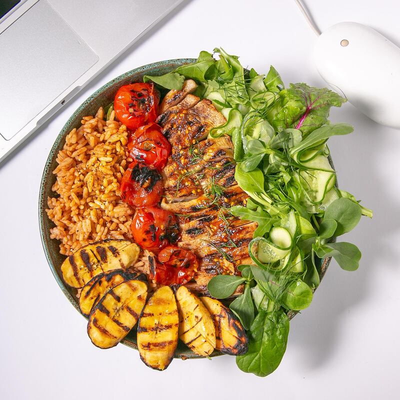 A dish from Catfish of grilled peri-peri chicken, plantain, cherry tomatoes, salad and jollof rice with pineapple sriracha dressing.