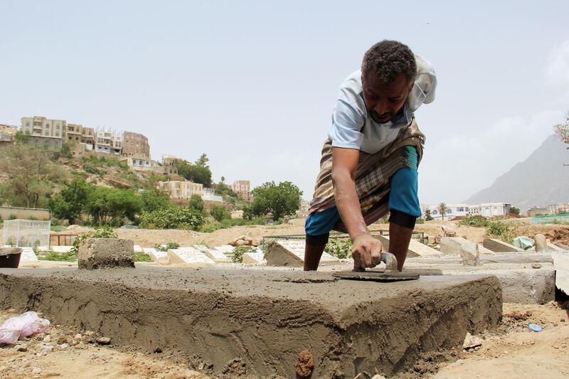 A worker builds a tombstone at a cemetery where victims of the coronavirus disease are buried in Taiz, Yemen. Reuters