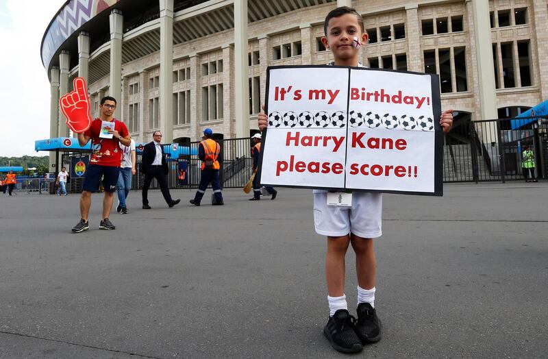 A young England supporter holds a sign supporting Harry Kane. EPA