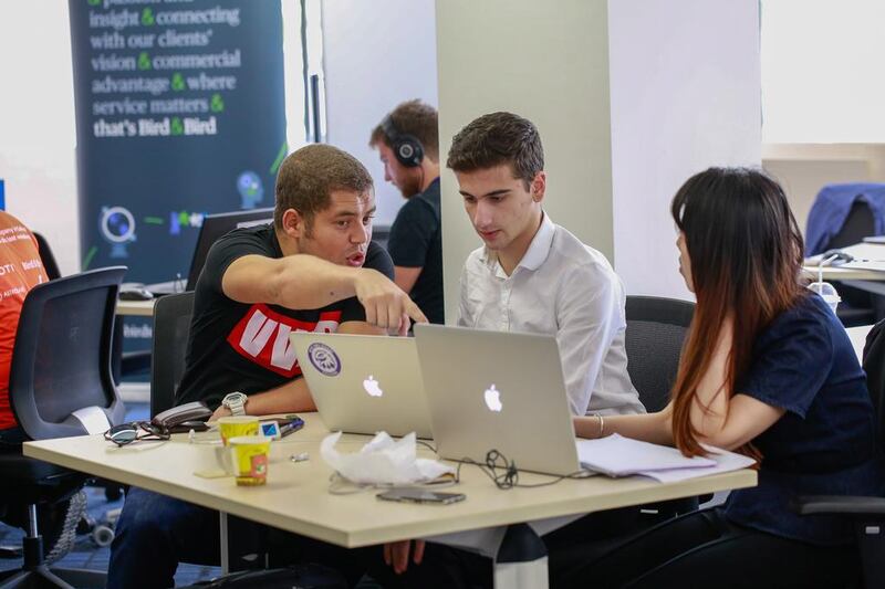 Saber Ghaith, left, Andrey Simeonov, centre, and Danni Luq discuss their team project at the Dubai Startup Weekend at Astrolabs Dubai. Victor Besa for The National