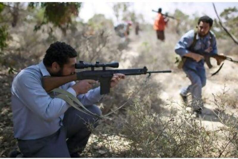 A rebel fighter points his gun as other comrades cross the front line between them and Qaddafi forces, 25 km west from Misrata yesterday. Rodrigo Abd / AP Photo