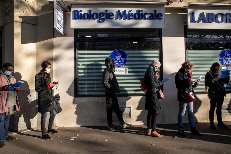Visitors uses smartphones while queuing outside a Covid-19 test center in Paris, France. Bloomberg