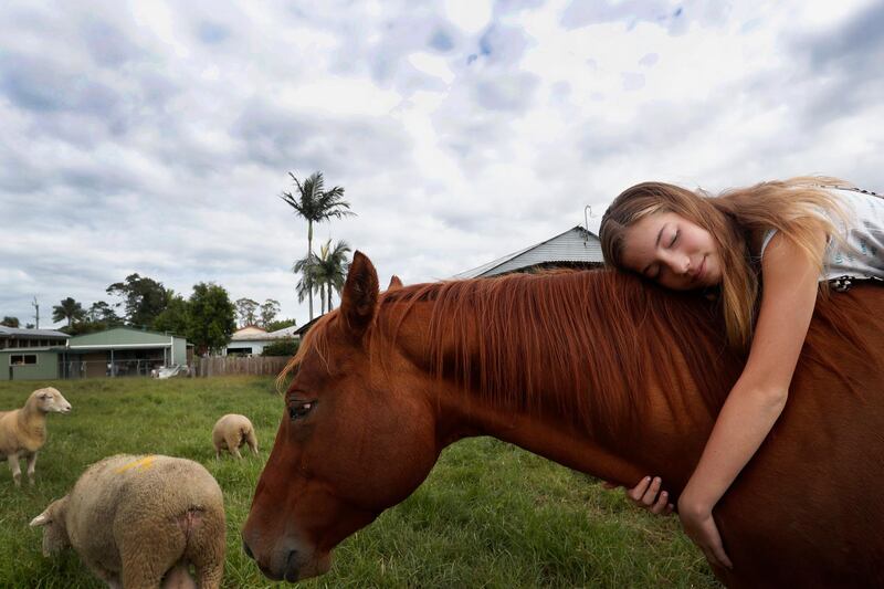 Mia Harris hugs her horse Sharny who survived the recent flooding that inundated her family home in the small township of Croki, in Taree, Australia, on March 29, 2021. Getty Images