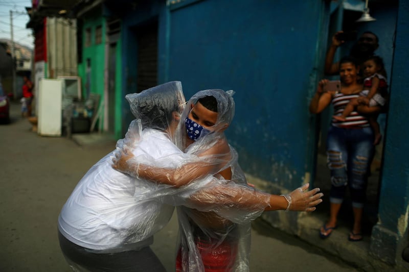 Teacher Maura Silva, who works for public school Escola Municipal Frei Vicente de Salvador and who created a "hug kit" using plastic covers, embraces her student Yuri Araujo Silva at Yuri's home in the 77 Padre Miguel slum in Rio de Janeiro, Brazil. Reuters