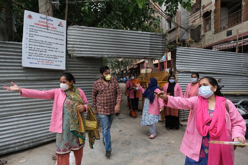 Workers with Accredited Social Health Activist (Asha) from India's National Rural Health Mission wearing pink robes and protective masks as they conduct a door-to-door survey on the coronavirus in New Delhi. Bloomberg