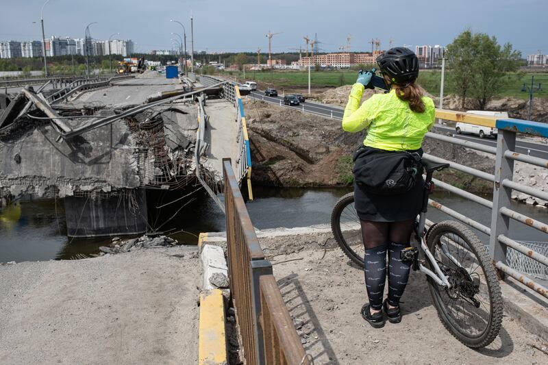 A cyclist photographs the destroyed bridge over the Irpin river, in Irpin. Getty Images