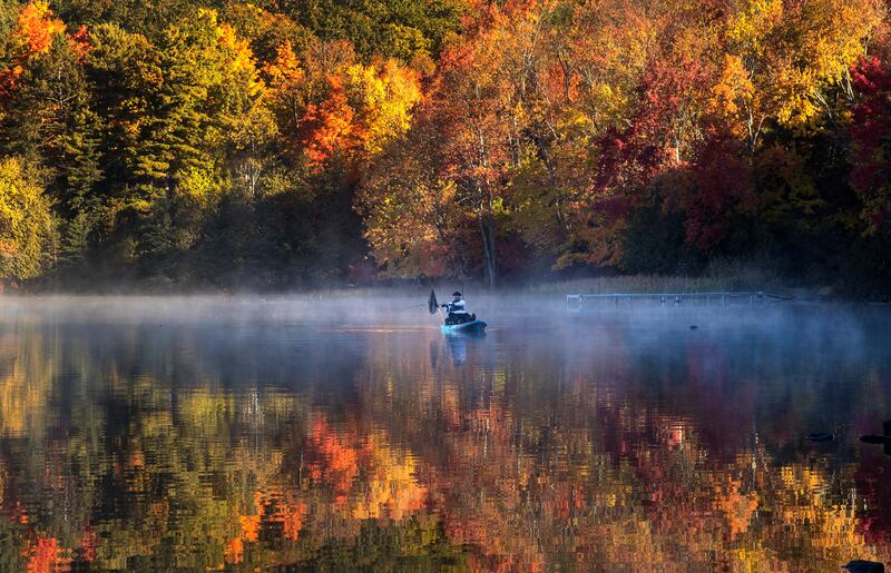 A fisherman in a kayak on Bass Lake is framed by autumn colours in central Ontario.  AP