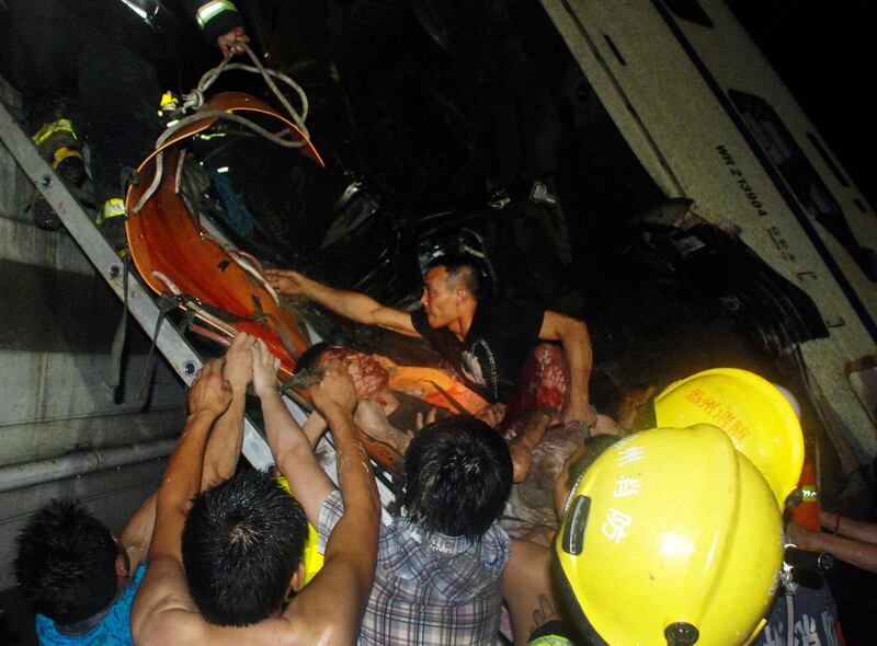 Emergency workers and civilians carry an injured passenger from the wreckage of a train crash in Wenzhou in east China's Zhejiang province, Saturday, July 23, 2011. A Chinese bullet train lost power after being struck by lightning and was hit from behind by another train, knocking two of its carriages off a bridge, killing at least 16 people and injuring 89, state media reported. (AP Photo) CHINA OUT *** Local Caption ***  China Train Crash.JPEG-06130.jpg