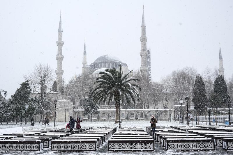 epa08945633 People enjoy their time in front of the Sultanahmet Mosque on a snowy day in Istanbul, Turkey, 18 January 2021.  EPA/SEDAT SUNA
