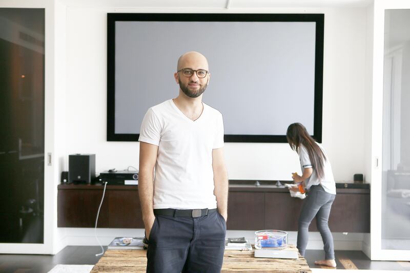 
DUBAI , UNITED ARAB EMIRATES , JULY 16 – 2017 :- Abdul Kareem Abdul Ghani founder of the MaidMe app at his apartment in Limestone House in DIFC in Dubai. One of the cleaning staff ( background ) working at his home. (Pawan Singh / The National) Story by Alice Haine
