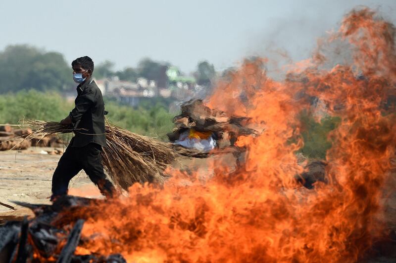 A worker walks past a funeral pyre of a person who died of Covid-19, at a cremation ground in India’s northern city of Allahabad.
