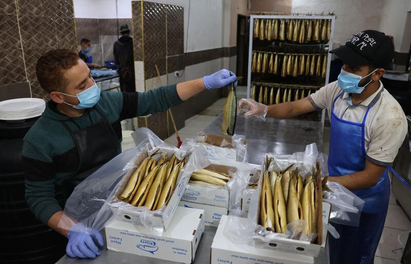 Palestinian youths prepare smoked mackerels to be sold at a fish market in the town of Rafah, in southern Gaza Strip. AFP