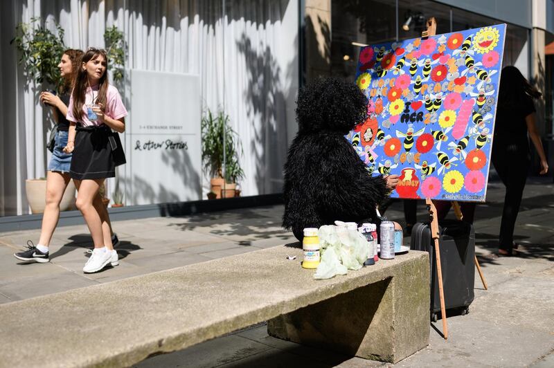 An artist paints a mural as people walk past, on the first anniversary of the terrorist attack in central Manchester, on May 22, 2018 in Manchester, England.  Getty