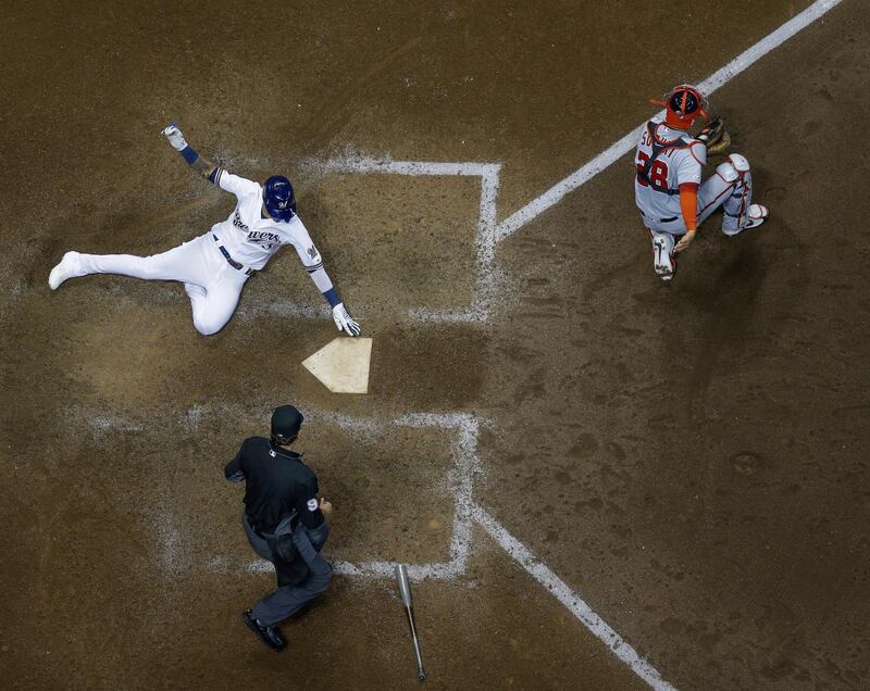 Milwaukee Brewers' Orlando Arcia scores past Washington Nationals catcher Kurt Suzuki during the eighth inning of a baseball game  in Milwaukee. AP