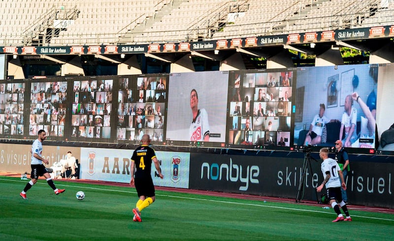 Players vie for the ball as fans are streamed live on to the screens on the sidelines during the 3F Super League football match between AGF and Randers FC. AFP