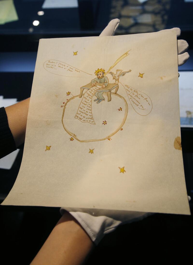 A staff member of the auction house Artcurial displays a watercolor illustration by Antoine de Saint-Exupery, done around 1942, in Paris, France, Friday, June 15, 2018. The illustration showing a likeness of Saint-Exupery's renowned Little Prince atop a globe, adorning an anguished love letter, has sold at auction for 240,500 euros ($289,460). (AP Photo/Michel Euler)
