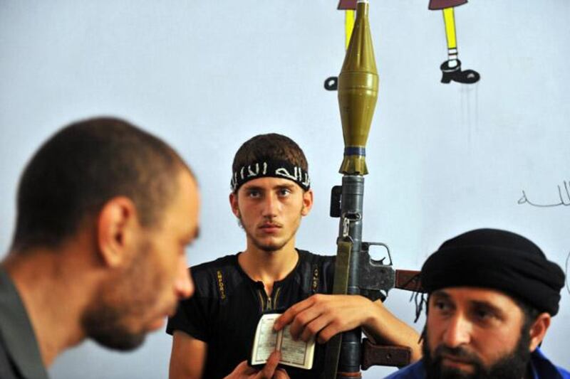 A fighter from the Syrian opposition holds a Koran, Islam's holy book, and a rocket-propelled grenade (RPG), as other rebels rest in a former primary school in the centre of Syria's restive northern city of Aleppo on July 25, 2012. The Syrian army and rebels on July 25, sent reinforcements to Aleppo to join the intensifying battle for the country's second city, as UN chief Ban Ki-moon urged the world "to stop the slaughter." AFP PHOTO / BULENT KILIC

