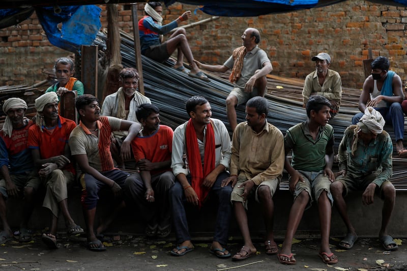 Workers who transport iron rods used in building construction take a break at a warehouse in Prayagraj, India.