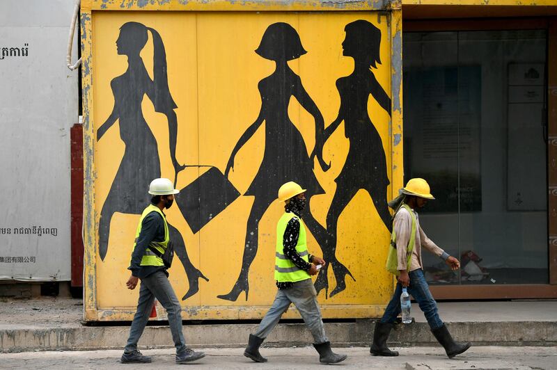 Construction workers pass a mural in Phnom Penh, the capital of Cambodia. AFP