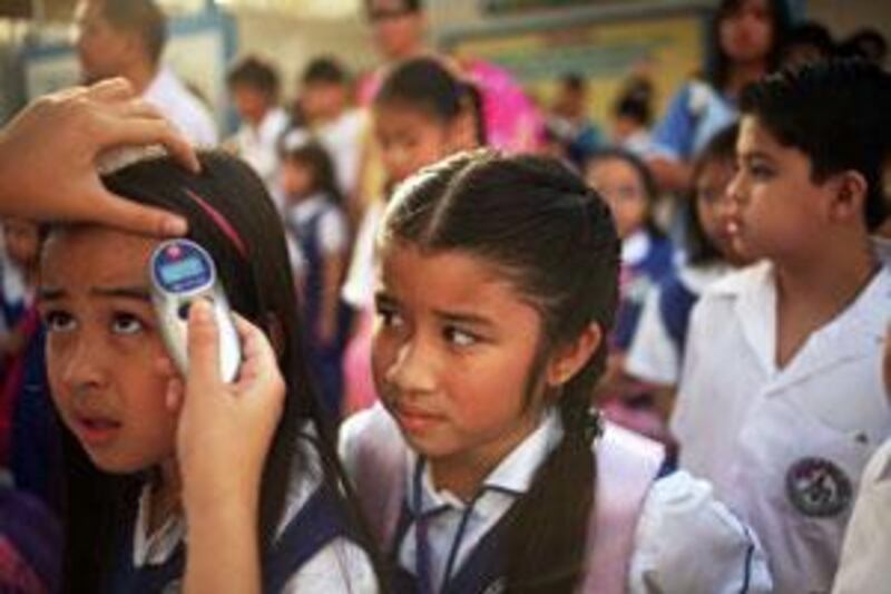 A nurse at Abu Dhabi's Philippine National School, checks pupils' temperature before they enter the classroom yesterday.