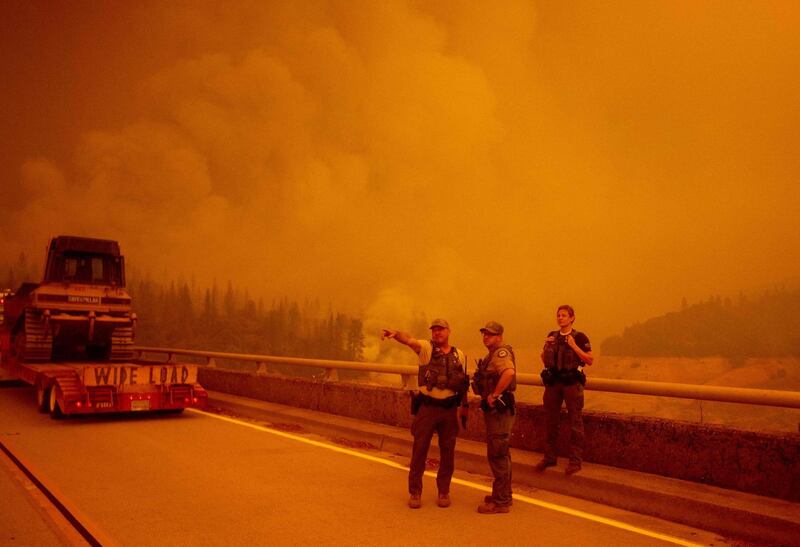 Law enforcement and fire personnel wait on the Enterprise Bridge to enter an area encroached by fire during the Bear fire, part of the North Lightning Complex fires, in unincorporated Butte County, in Oroville, California.  AFP