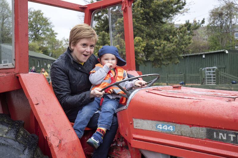 Nicola Sturgeon poses with three-year-old Christopher Mutch in a tractor during a campaign visit to LOVE Gorgie Farm in Edinburgh. AFP