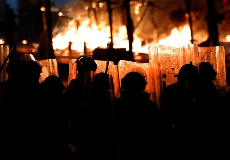 Riot policemen watch flames rise from the tents of anti-government protesters in Beirut. AP Photo