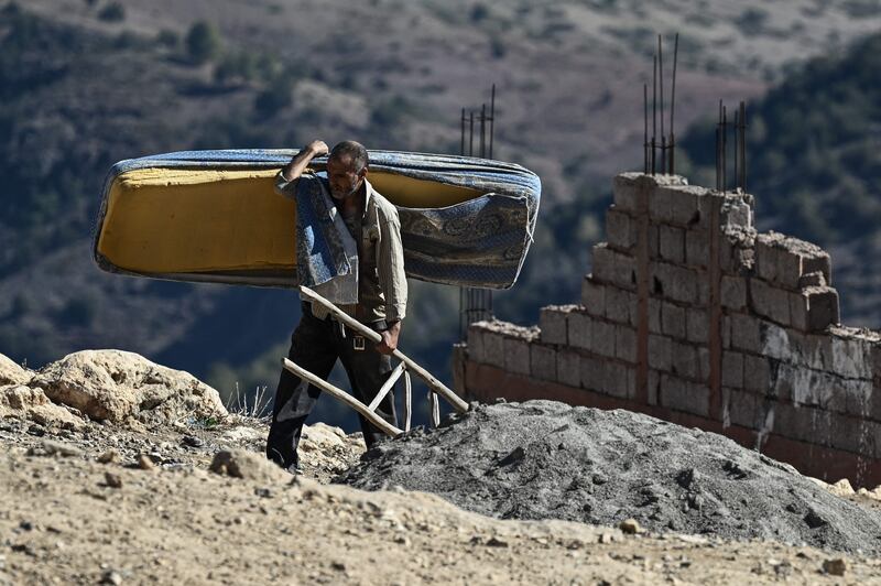 A man carries some of his belongings after his home was destroyed in the earthquake in Moulay Brahim. AFP