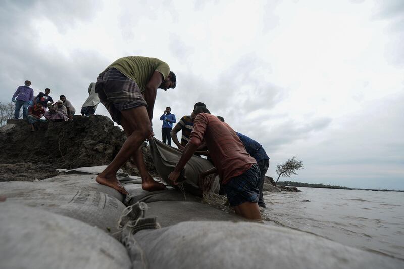 Volunteers and residents place sack filled with soil to repair a damaged dam following the landfall of cyclone Amphan in Burigoalini. At least 84 people died as the fiercest cyclone to hit parts of Bangladesh and eastern India this century sent trees flying and flattened houses, with millions crammed into shelters despite the risk of coronavirus.  AFP