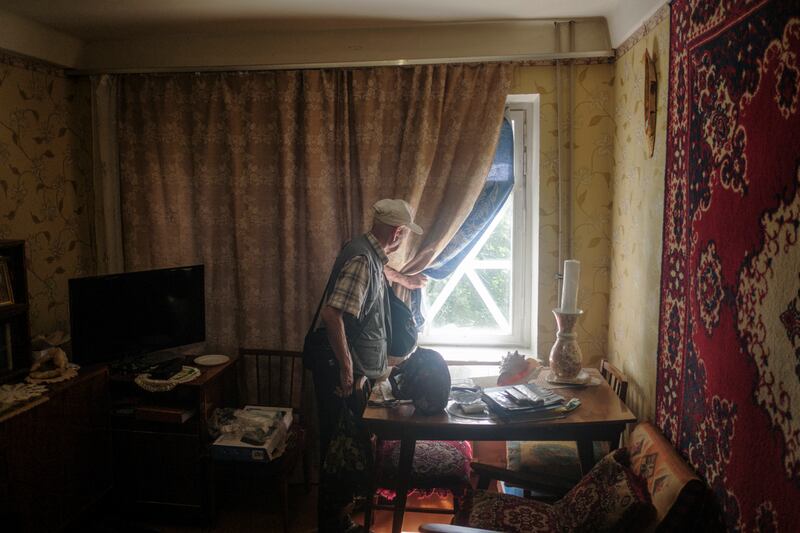 A Kramatorsk resident peers out of a window lined with tape to reduce the impact of shattering glass. EPA