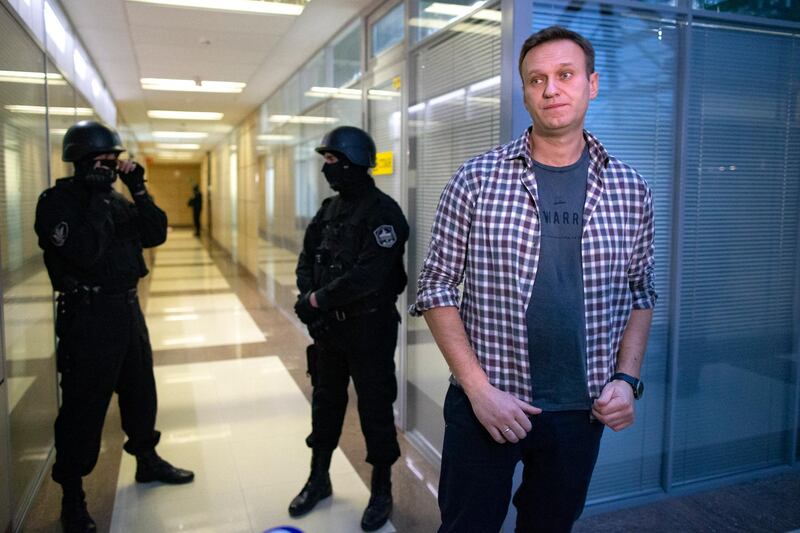 FILE - In this Thursday, Dec. 26, 2019 file, Russian opposition leader Alexei Navalny speaks to the media in front of security officers standing guard at the Foundation for Fighting Corruption office in Moscow, Russia. A court is expected to outlaw the organizations founded by Russian opposition leader Alexei Navalny. Prosecutors have asked the Moscow City Court to designate Navalny's Foundation for Fighting Corruption and his sprawling network of regional offices as extremist organizations. The extremism label also carries lengthy prison terms for activists who have worked with the organizations, anyone who donated to them, and even those who simply shared the groups' materials. (AP Photo/Alexander Zemlianichenko, File)