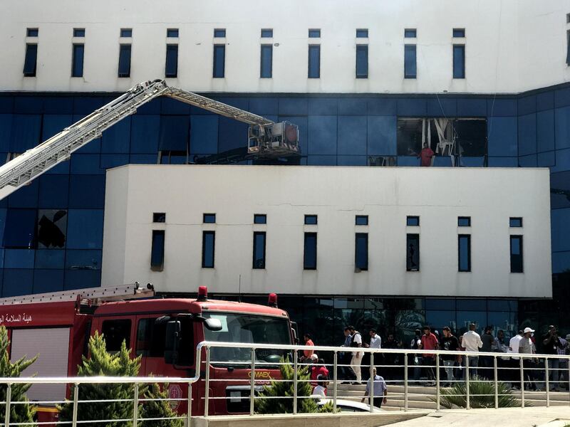 Firefighters and onlookers gather in front of the oil company building. AFP