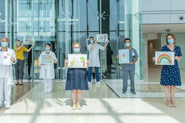 Caregivers at Cleveland Clinic Abu Dhabi hold up artworks by students at Aspen Heights British School. Courtesy Cleveland Clinic