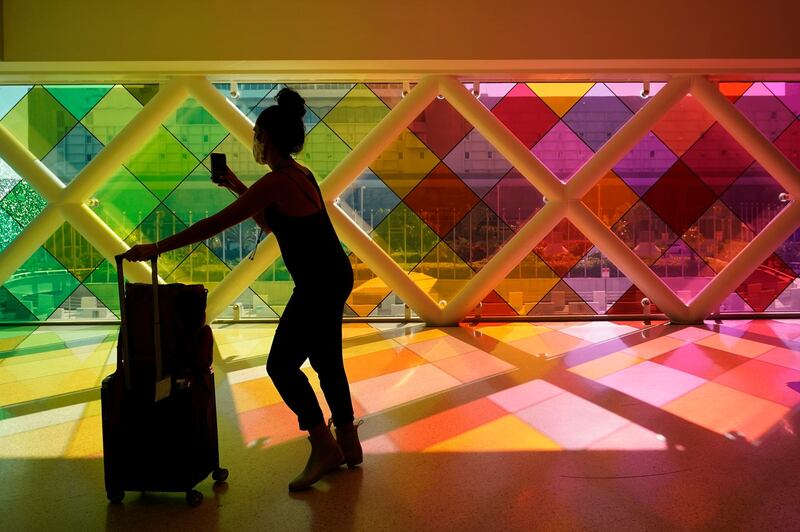 A traveller takes photos of windows titled "Harmonic Convergence," by artist Christopher Janney, at Miami International Airport in Miami. The Greater Miami Convention and Visitors Bureau is anticipating hotel occupancy levels to surge above pre-pandemic levels. AP Photo