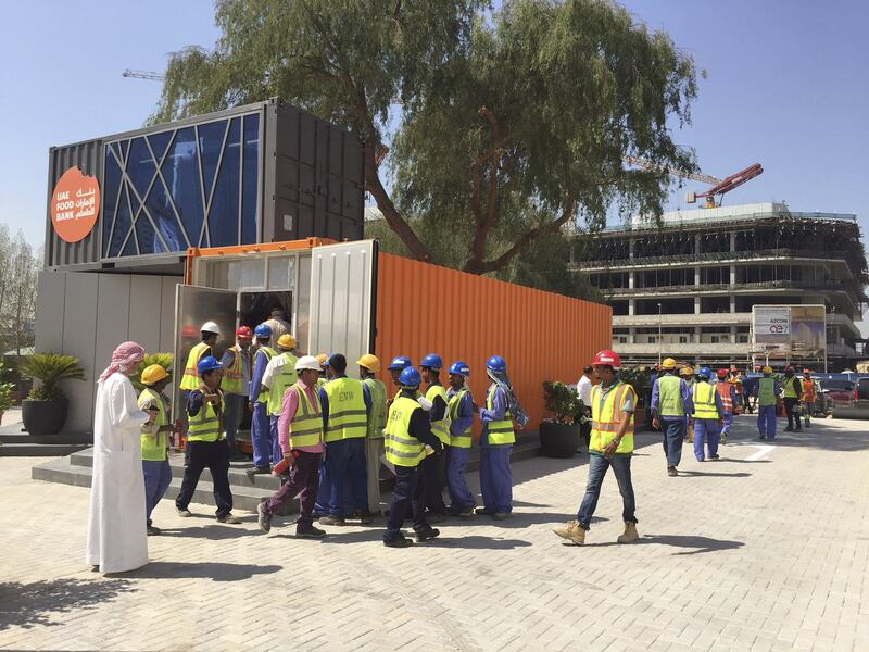 Workers are given food on Monday at the launch of a new Food Bank site in Al Bada, Dubai. Ramola Talwar Badam / The National