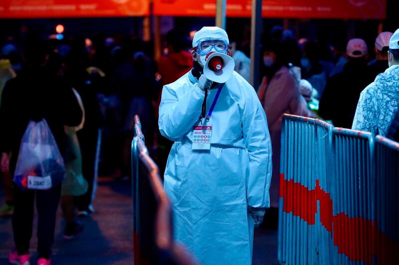 A staff member in a protective suit speaks through a loudspeaker ahead of the 2020 Shanghai marathon. AFP