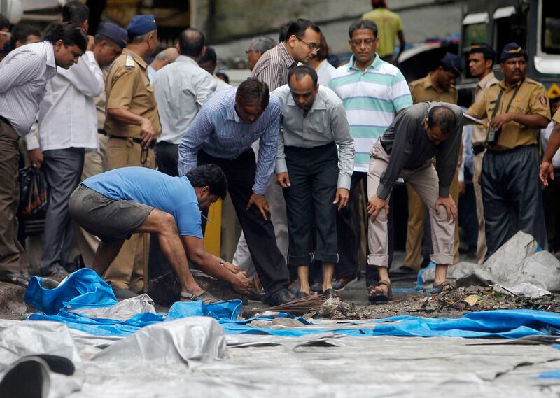 A man moves debris during a clean-up operation near the Opera House, one of the sites of Wednesday's triple explosions, in Mumbai July 15, 2011. Indian Prime Minister Manmohan Singh vowed on Thursday to bring to justice those behind the triple bomb attacks on Mumbai, and police questioned members of home-grown Islamist militant group Indian Mujahideen. REUTERS/Vivek Prakash (INDIA)