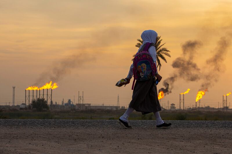 A girl carries her school bag as she walks in the Nahr Bin Omar village, across from the eponymous oil field and facility in Iraq's southern Basra governorate. AFP