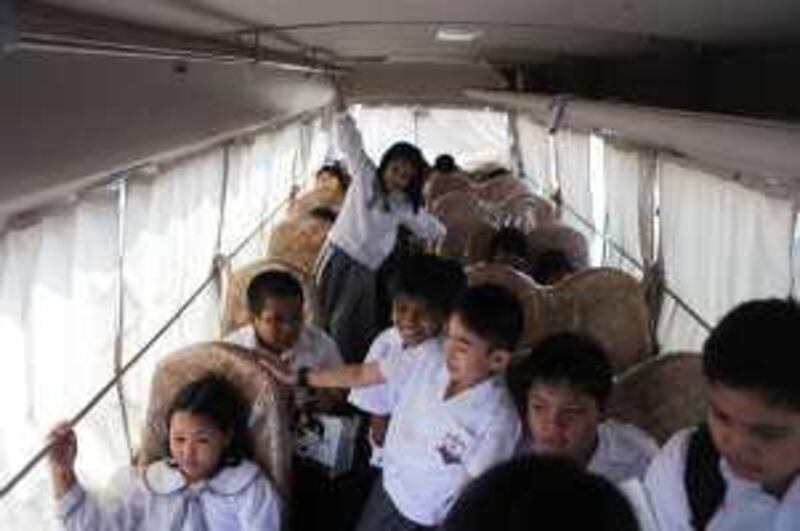 united arab emirates - abu dhabi - september 1st, 2009:  Kids settle down into their seats on the bus at the Pisco Private School in Abu Dhabi.  (Galen Clarke/The National) for bus safety story *** Local Caption ***  GC06_09012009_Bus.jpg