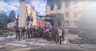 Chechen President Ramzan Kadyrov's Telegram channel shows forces loyal to Russia waving national flags against a backdrop of destroyed buildings in Lysychansk. AP