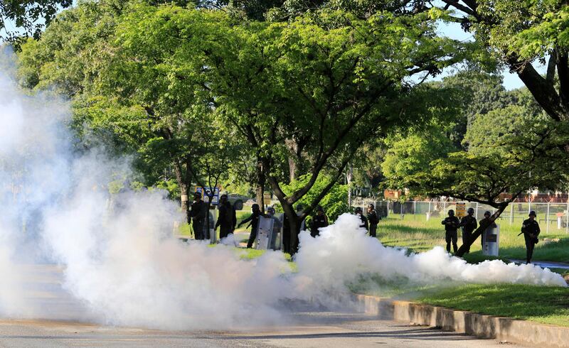 Venezuelan Bolivarian National Guard officers fire teargas toward a resident who tries to walk to the Paramacay military base in Valencia, Venezuela, Sunday Aug. 6, 2017. Venezuelan ruling party chief Diosdado Cabello said the military squashed a "terrorist" attack at the military base Sunday, shortly after a small group of men dressed in military fatigues released a video declaring themselves in rebellion. (AP Photo/Juan Carlos Hernandez)