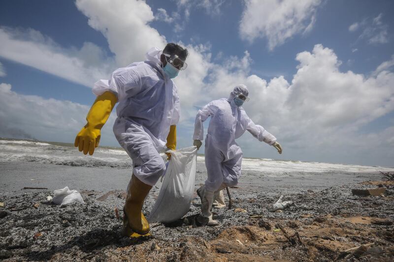 Military personnel involved in clearing beaches wear protective clothing. The 'MV X-Press Pearl' was carrying a chemical cargo when it caught fire off Sri Lanka. EPA