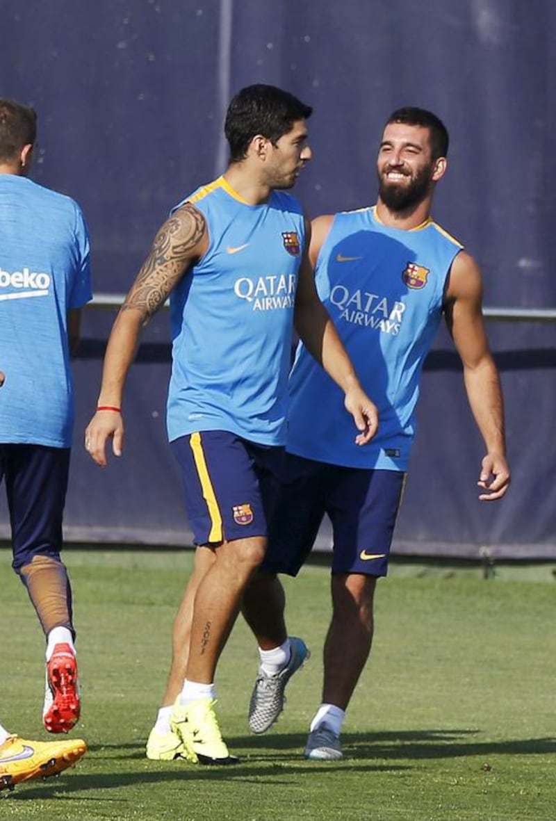 Arda Turan, right, and Luis Suarez share a joke during training. Josep Lago / AFP / July 13, 2015